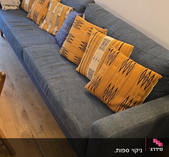 ספה כחולה עם כריות כתומות ודוגמה גיאומטרית